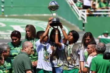 Familiares de los fallecidos levantan el trofeo.