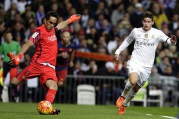 El portero chileno del FC Barcelona, Claudio Bravo, despeja la pelota ante el centrocampista colombiano del Real Madrid, James Rodríguez.