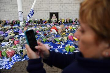 A woman uses a smartphone in front of tributes outside Leicester City Football Club's King Power Stadium in Leicester