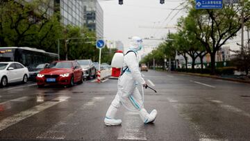 FILE PHOTO: A worker wearing a protective suit and carrying disinfection equipment crosses a road amid the coronavirus disease (COVID-19) outbreak in Beijing, China April 27, 2022. REUTERS/Carlos Garcia Rawlins/File Photo