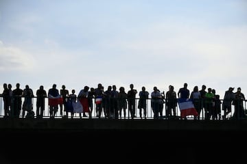 France's fans hold French national falgs as they wait on a bridge over the high way for the bus transporting the France's national football team riding towards Paris, on July 16, 2018 after winning the Russia 2018 World Cup final football match. / AFP PHO