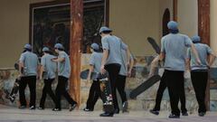 Un mismo skater clonado varias veces con pantalones negros, tabla de skate, camiseta clara y gorra azul, andando frente a un spot en el que ha intentado un truco. 