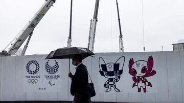 Un hombre con mascarilla pasa por delante de una zona de obras de los Juegos Olímpicos de Tokio.