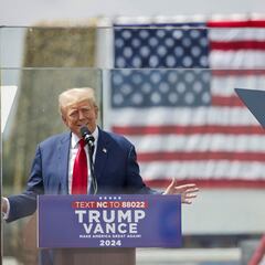 Why is Donald Trump surrounded by glass in his campaign meetings?