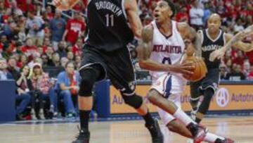 Jeff Teague trata intenta lanzar a canasta ante el acoso de Brook Lopez.
