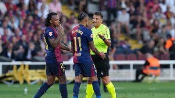 BARCELONA, 24/08/2024.- Los jugadores del FC Barcelona Raphinha (c) y Jules Koundé (i) discuten una decisión arbitral con el colegiado Gil Manzano (d) durante el partido de la segunda jornada de LaLiga EA Sports, entre el FC Barcelona y el Athletic de Bilbao, en el Estadio Olímpico de Montjuic, en Barcelona. EFE/Alejandro García