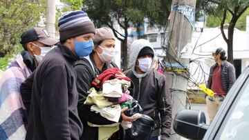 AME9656. QUITO (ECUADOR), 13/05/2020.- Migrantes venezolanos, que permanecen a la salida de la sede de la Embajada Venezolano en Quito esperando ser repatriados a su pa&iacute;s, reciben una donaci&oacute;n de ropa y alimentos de parte de ciudadanos ecuat