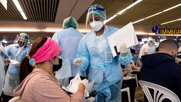 (FILES) In this file photo taken on August 11, 2021, airport staff wearing personal protective equipment (PPE) check the documentation of passengers arriving at Thailand's Phuket International Airport, as part of the "Phuket sandbox" scheme for travellers fully vaccinated against the Covid-19 coronavirus to visit without quarantine. - Thailand is to cut the quarantine for vaccinated travellers to seven days starting in October, officials said on September 27, 2021, as it seeks to revive its battered tourism industry. (Photo by Jack TAYLOR / AFP)