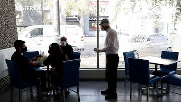 Un mesero protegido con máscara atiende una mesa en el restaurante "Punta Sal" el pasado 20 de julio, en Lima (Perú). EFE /Paolo Aguilar