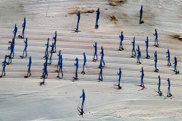 En la imagen aparece un grupo de participantes en la carrera popular de esquí nórdico Nordi Cki Marxa Beret que se disputa en Baqueira Beret (Lleida). El fotógrafo ha tomado una preciosa fotografía en la que la perspectiva hace que se vean sombras enormes de los deportistas, que apenas llegan a ser apreciados. 