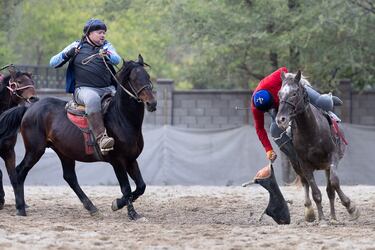 Un jinete se inclina al límite para levantar el trofeo simbólico del juego.