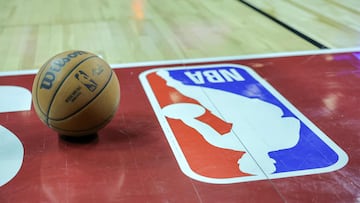 A basketball is placed on the court next to an NBA logo.