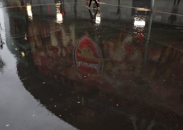 El escudo del Arsenal se refleja en el charco provocado por las lluvias de Londres antes del encuentro frente al PSV.