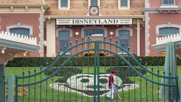 An employee cleans the grounds behind the closed gates of Disneyland Park on the first day of the closure of Disneyland and Disney California Adventure theme parks.