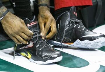 LeBron James se ata los cordones de sus zapatillas donde lleva escrito un mensaje.