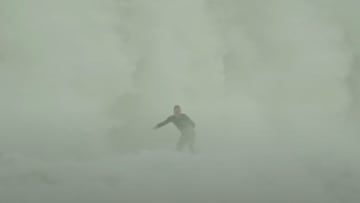 Una ola gigante rompe tras un surfista, generando una espuma blanca gigante, en invierno del 2023. 