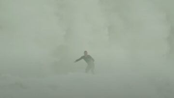 Una ola gigante rompe tras un surfista, generando una espuma blanca gigante, en invierno del 2023.