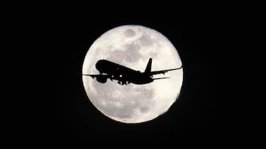 Un avión de pasajeros vuela frente a la Luna mientras se eleva sobre la Bahía de San Francisco en San Mateo, California, Estados Unidos.