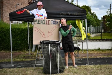 Los espectadores se alinean a lo largo del recorrido de la carrera con una cesta de red para recoger las botellas de hidratación de los ciclistas (llamadas "bidones") durante la tercera etapa de la 112.ª edición del Tour de Francia,  entre Valenciennes y Dunkerque.