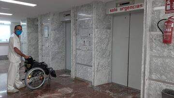 Imagen de un profesional sanitario llevando una silla de ruedas hacia el ascensor del hospital.