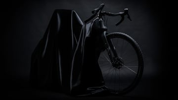 La primera bicicleta el&eacute;ctrica de Crow Bicycles, de Gravel, muestra su rueda delantera y manillar, con luz oscura y fondo negro, tapando el resto de la e-bike con una manta negra. 