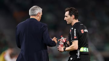El árbitro Ricardo De Burgos recoge las botellas lanzadas al terreno de juego tras el segundo gol del Sevilla FC.