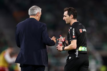 El árbitro Ricardo De Burgos recoge las botellas lanzadas al terreno de juego tras el segundo gol del Sevilla FC.