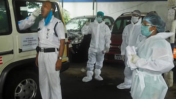 A health worker collects a swab sample of a policeman to test for the COVID-19 coronavirus, from an ambulance at a police station in Kolkata on July 28, 2020. - A health worker wearing a protective suit walks in a police station to collect swab samples fr