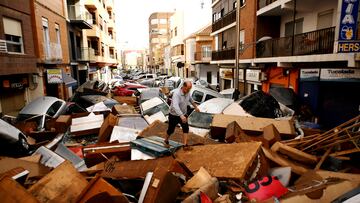 Un hombre intenta avanzar sobre una calle llena de vehículos amontonados  en el área de Sedaví en Valencia, España.