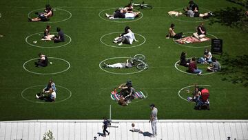 People are seen practising social distancing in white circles in Domino Park, during the Covid-19 pandemic on May 17, 2020 the in Brooklyn borough of New York City. (Photo by Johannes EISELE / AFP)