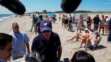 People on the beach look on as Joe Biden speaks with reporters during a walk with family members near Gordons Pond in Cape Henlopen State Park, Rehoboth Beach, Delaware.