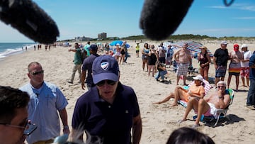 People on the beach look on as Joe Biden speaks with reporters during a walk with family members near Gordons Pond in Cape Henlopen State Park, Rehoboth Beach, Delaware.