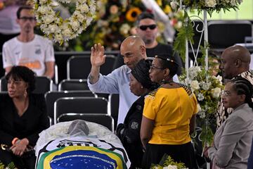 Edinho, hijo de Pelé, saluda a las personas que pasan junto al ataúd de su padre durante su funeral en el Estadio Urbano Caldeira.