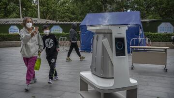 BEIJING, CHINA - MAY 13: A woman and child look at a disinfectant robot as it works at a nucleic acid testing site for COVID-19 on May 13, 2022 in Beijing, China. China is trying to contain a spike in coronavirus cases in the capital Beijing after hundreds of people tested positive for the virus in recent weeks, causing local authorities to initiate mass testing, mandate proof of a negative PCR test within 48 hours to enter many public spaces, to close schools and retail stores, ban gatherings and inside dining in all restaurants, and to lockdown many neighbourhoods in an effort to maintain the country's zero COVID strategy. (Photo by Kevin Frayer/Getty Images)