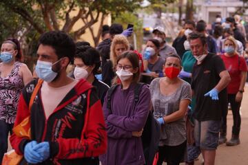 Colas de personas que esperan para recibir ayuda en un centro de distribución de ropa y comida en Valencia. 
 