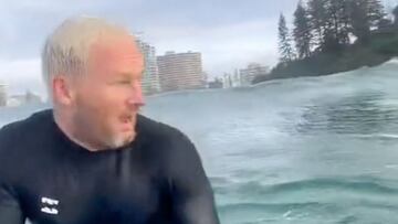 Dan Leyshon, sentado sobre su tabla de surf, con cara de susto al ver algo a su lado en Snapper Rocks (Gold Coast, Australia), en mayo del 2022.