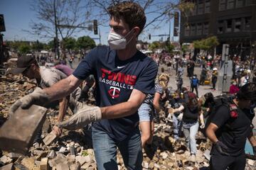 MINNEAPOLIS, MN - MAY 30: People work to clean up outside a burned building on May 30, 2020 in Minneapolis, Minnesota. Buildings and businesses around the Twin Cities have been looted and destroyed in the fallout after the death of George Floyd while in police custody. Police Officer Derek Chauvin has been charged with third-degree murder and manslaughter in Floyd's death. Stephen Maturen/Getty Images/AFP == FOR NEWSPAPERS, INTERNET, TELCOS & TELEVISION USE ONLY ==