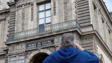 A man takes a picture of a broken window protected by a wooden panel at the Louvre Museum as the museum remains closed the day after a spectacular jewel heist by thieves who broke into the landmark by using a crane and smashing an upstairs window, stealing priceless jewelry from an area that houses the French crown jewels before escaping on motorbikes, in Paris, France, October 20, 2025. REUTERS/Benoit Tessier