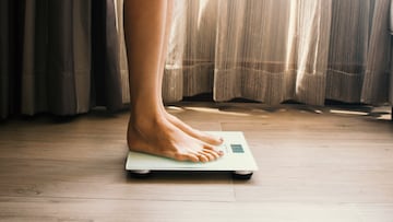A low-angle view of a young woman who is weighing herself in a weighing scale