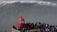 Una ola gigante en el pico Big Mama de Praia do Norte, a punto de romper, mientras decenas de personas se lo miran desde el Fuerte de San Miguel Arc&aacute;ngel en Nazar&eacute; (Portugal), el 25 de febrero del 2022. 