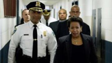 La fiscal Loretta Lynch es acompa&ntilde;ada por un polic&iacute;a de Baltimore.