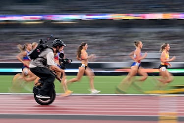 Un camarógrafo en un monociclo filma a atletas en acción mientras compiten en la final femenina de 3000 metros con obstáculos durante el Campeonato Mundial de Atletismo en Tokio. 