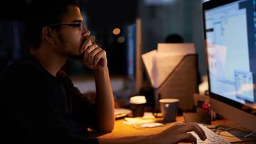 Shot of a young programmer working in a dimly-lit office