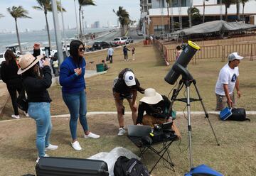 La gente se reúne para preparar equipos para observar el sol en el Malecón, un día antes de un eclipse solar total en Mazatlán, México.