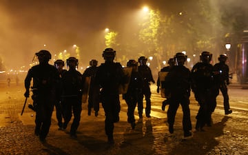 La policía antidisturbios tiene que intervenir en la avenida de los Campos Elíseos durante las celebraciones de la victoria del PSG en las calles de París.
