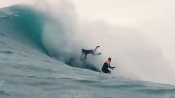 El surfita Lucas Chianca agarrado a un jet ski mientras sufre un wipeout en Nazar&eacute; (Portugal) e intenta evitar chocar con el surfista Ian Cosenza, surfeando justo delante suyo, en Nochebuena del 2021. 