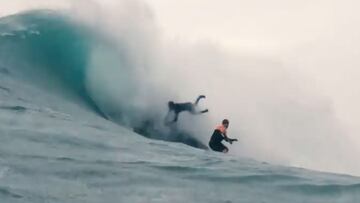 El surfita Lucas Chianca agarrado a un jet ski mientras sufre un wipeout en Nazaré (Portugal) e intenta evitar chocar con el surfista Ian Cosenza, surfeando justo delante suyo, en Nochebuena del 2021.