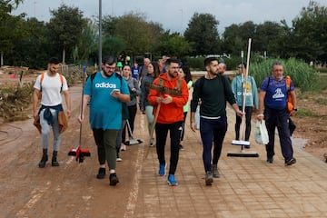 Personas transportan suministros para ayudar a las zonas afectadas por las inundaciones caminan por un camino fangoso, tras las lluvias torrenciales que provocaron inundaciones, en Valencia.