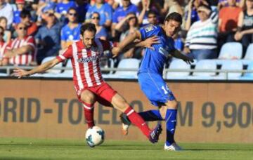 El defensa del Atlético de Madrid Juanfran (i) lucha un balón con el centrocampista del Getafe Pedro León, en el partido de la trigésima tercera jornada de liga de Primera División disputado esta tarde en el Coliseo Alfonso Pérez de Getafe.
