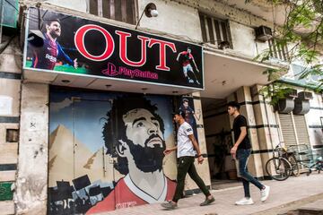 J¨®venes egipcios llegan al cibercaf¨¦ de PlayStation en el centro de El Cairo con su entrada decorada con im¨¢genes de Mohamed Salah, junto al delantero argentino Lionel Messi y el portugu¨¦s del Real Madrid, Cristiano Ronaldo